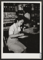 [recto] Miss Rose Utsunomiya, recently from Jerome, and her friend, Judy Schwartz, are busily preparing capsules in the Pharmacy Department of the large Jefferson Hospital. Both are also working for their degrees at the Philadelphia College of Pharmacy and Scienc