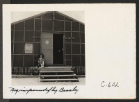 [recto] Tanforan Assembly Center, San Bruno, Calif.--Young evacuee on steps of the library which has just been established at this assembly center under the direction of a Mills College graduate, a professional librarian of Japanese ancestry. ;  Photographer: L