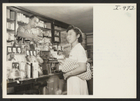 [recto] Mr. William Toshiyuki, owner and operator of the West Fresno Drug Co., is shown selling some cosmetics to Tsuyako Yamashiro, ...