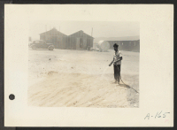 [recto] Poston, Ariz. (Site #1)--Jim Morikawa sprinkling to settle the dust at this War Relocation Authority center for evacuees of Japanese ancestry. ;  Photographer: Clark, Fred ;  Poston, Arizona.