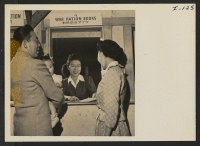 [recto] Fumi Taketa of the War Ration Book Department issues War Ration Books to Mr. and Mrs. Thomas Oki, as they ...