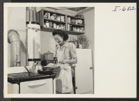 [recto] Mrs. Thomas Taneichi Kamikawa is preparing supper in the kitchen of the 4-room family unit which she occupies with her ...
