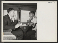 [recto] Roscoe Bell, W.R.A. representative on trip 15, Topaz to Tule Lake, checks with the car captains as to the comfort and well being of passengers in their respective cars. ;  Photographer: Mace, Charles E. ; , .