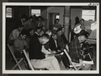 [recto] Vocational training class in farm construction gets some real action at the Central Utah Relocation Center. Picture shows a classroom exercise with instructor Gardener at rear right. ;  Topaz, Utah.
