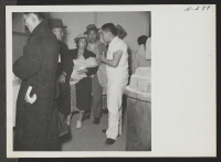 [recto] Former residents of Tule Lake arriving at the induction center at Topaz, Utah, are shown being checked by one of the resident physicians as they pass through to their new quarters. ;  Photographer: Mace, Charles E. ;  Topaz, Utah.