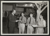 [recto] Boy Scouts hold a Court of Honor at Central Utah Relocation Center. Project Director Charles, E. Ernst presents certificates of merit to Scout Masters of three center troops. (Left to Right: Kenji Okawachi, Frank Marucha, Vernon Ichisaka). ;  Topaz, Uta