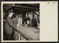 [recto] An elderly evacuee purchases peanut butter for a between meal snack. All meals for the residents are served in mess halls, and are merely supplemented by tid bits which the evacuees prepare in their own barracks. ;  Photographer: Stewart, Francis ;  M