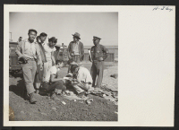 [recto] Wardens in charge of the distribution of the loading of baggage and freight check over their lists after loading a car destined for Heart Mountain. ;  Photographer: Mace, Charles E. ;  Newell, California.
