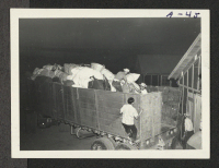 [recto] Evacuees unloading their baggage. ;  Poston, Arizona.
