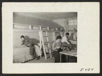 [recto] The Ninomiya family in their barracks room at the Amache Center. The mother's handiwork in preparing drapes, fashioning furniture out ...