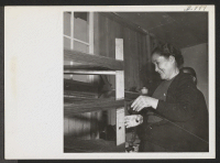 [recto] This Issei woman is winding yarn in the weaving room at Rohwer Relocation Center. ;  Photographer: Van Tassel, Gretchen ;  McGehee, Arkansas.
