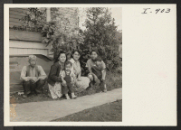 [recto] The Sukemon Itami family, formerly from Heart Mountain, is shown in front of their Portland home. Left to right: Mr. ...