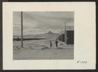 [recto] Looking west on F Street [i.e. Avenue G?], main thoroughfare of this relocation center, with its namesake Heart Mountain looming in the background. ;  Photographer: Parker, Tom ;  Heart Mountain, Wyoming.