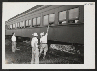[recto] A Minidoka Relocation Center evacuee and an evacuee being transferred to the Tule Lake Center grasp hands in a final farewell as the train carrying the 254 evacuees to the Tule Lake Center prepares to leave. ;  Hunt, Idaho.