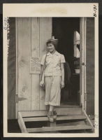 [recto] Manzanar, Calif.--In the doorway of her barrack apartment at this War Relocation Authority center for evacuees of Japanese ancestry. ;  Photographer: Albers, Clem ;  Manzanar, California.