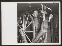 [recto] There is provision for weaving and spinning at Rohwer Relocation Center. This man has grown his own cotton on a little plot by his barrack. Here he is spinning it into thread preparatory to weaving it. ;  Photographer: Van Tassel, Gretchen ;  McGehee,