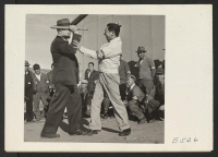 [recto] The loop on a police club and its long handle are used for more than carrying as Chief of Internal Security Tomlinson demonstrates to a class of center civilian police. ;  Photographer: Parker, Tom ;  Amache, Colorado.