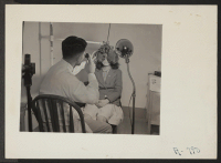 [recto] Dr. examining eyes of girl. George Tani, optometrist. Former occupation: optometrist. Former residence: Oakland, California. ;  Photographer: Stewart, Francis ;  Hunt, Idaho.