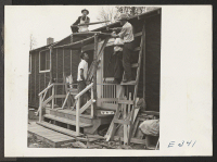 [recto] Adding a front porch to their barracks, these centerites are thinking of winter snow and rain. ;  Photographer: Parker, Tom ;  McGehee, Arkansas.