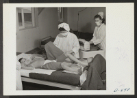 [recto] Registered Nurse, Mrs. Edythe Sasser, is assisted by Yoshiko Konatsu, Nurse's Aid, and Tomiko Kitasaki, Nurse's Aid, in the treatment ...