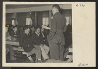 [recto] Lt. Eugene Bogard explains the purpose of registration to a group of Japanese and Japanese-Americans who are now residing at this center. ;  Photographer: Stewart, Francis ;  Manzanar, California.