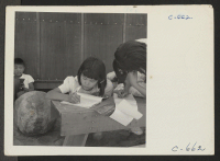 [recto] Manzanar, Calif.--Evacuee children of the 5th grade struggling over their English composition in the first temporary voluntary school at this War Relocation Authority center. ;  Photographer: Lange, Dorothea ;  Manzanar, California.