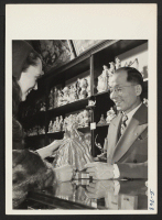[recto] Harry S. Oshimo, an Issei resident of Kansas City for ten years, in his gift shop on Petticoat Lane in ...