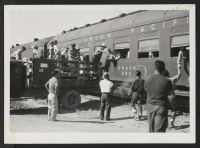 [recto] Loading hand baggage aboard parting train. ;  Topaz, Utah.