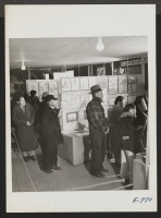 [recto] Evacuee residents at the Granada Relocation Center, viewing exhibits at the Arts and Crafts Festival in Terry Hall, March 6th to 8th. This festival was sponsored by the Educational Division and the Pioneer, center newspaper. ;  Photographer: Coffey, Pat