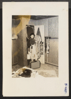 [recto] Arcadia, Calif.--Mrs. Lily Okura, with necktie rack, carpet and shelves, begins housekeeping at Santa Anita Park assembly center for evacuees of Japanese ancestry. Evacuees are transferred later to War Relocation Authority centers for the duration. ;  P