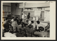 [recto] Leo W. Kraus instructing high school in class properties of wood. ;  Amache, Colorado.