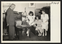 [recto] Mrs. George Sumida plays a record at the Brooklyn Hostel for Japanese Americans for Judge William F. Hagarty, chairman of ...