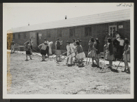 [recto] Hunt High school students clean and rake the areas between classroom barrack buildings preparatory to planting rye-grass. ;  Hunt, Idaho.