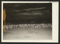 [recto] Part of the approximately 1,000 dancers who participated in the Bon Odori festival sponsored by the Granada Buddhist Church on August 14. Spectators are shown in the background. The dance was held at night on the baseball diamond. ;  Photographer: McCle