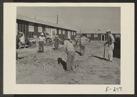 [recto] Evacuee work crews repairing drainage ditches and walks between the barracks at this relocation center. ;  Photographer: Parker, Tom ;  Denson, Arkansas.