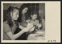 [recto] Young enthusiasts in a craft shop at the Heart Mountain Relocation Center. Scarcity of small art objects to relieve the bareness of barracks homes has made the craft shops popular with young and old residents of Japanese ancestry at this center. ;  Phot