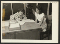 [recto] Esther Okuda, evacuee student, registers with her social service employer, Miss Virginia Ransland, for permission to leave the center and attend Colorado State Teachers College at Greeley, Colorado. ;  Photographer: Parker, Tom ;  Amache, Colorado.