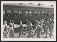 [recto] OUTGOING--Boy Scout band arriving at the train. ;  Photographer: Aoyama, Bud ;  Heart Mountain, Wyoming.