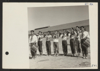 [recto] A drum and bugle corps, formerly a boy scout unit in Los Angeles, performs the dedication of a new hospital at Topaz. ;  Photographer: Parker, Tom ;  Topaz, Utah.
