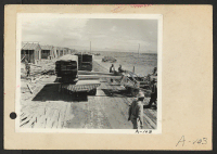 [recto] Poston, Ariz.--Site No. 1. Unloading lumber with bulldozer in the construction of barracks for evacuees of Japanese ancestry who will spend the duration in War Relocation Authority centers. ;  Photographer: Clark, Fred ;  Poston, Arizona.