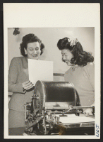 [recto] Mary Murata, formerly of Marysville, California, and the Granada Center, discusses a mimeographing job with her supervisor in the office ...