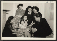 [recto] Former S/Sgt. Henry H. Gosho, Mrs. Gosho (seated) and their eighteen-month-old daughter Carol Jeanne are shown with a few of ...
