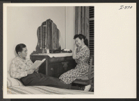 [recto] Mr. and Mrs. Kenji Sumi, Issei from the Heart Mountain Relocation Center, are relaxing in the bedroom of the furnished ...