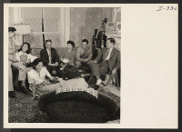 [recto] This group of resettlers is gathered in the attractively furnished living room of Mr. and Mrs. Eishichiro George Koiwai, Issei ...