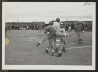 [recto] An exciting bit of action between the All Star and the Jack Rabbit football teams, during a game at the Heart Mountain Relocation Center. At the moment it is difficult to say who has the ball. ;  Photographer: Iwasaki, Hikaru ;  Heart Mountain, Wyomin