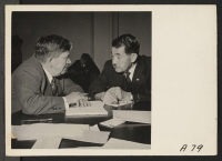 [recto] A business man of Japanese descent confers with a representative of the Federal Reserve Bank at Wartime Civil Control Administration ...