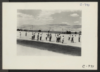 [recto] Manzanar, Calif.--Evacuees watching a baseball game at this War Relocation Authority center. This is a very popular recreation with 80 teams having been formed throughout the Center. Most of the playing is in the wide firebreak between blocks of barracks.