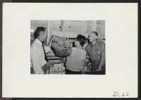 [recto] Tule Lake, Newell, Calif.--Kendall Smith, Assistant Supervisor of Community Enterprises, on left and Mortimer Cooke, Supervisor of Community Enterprises, on right, assist John Ito, store manager, in arranging stock at the Community Store No. 1. ;  Photo