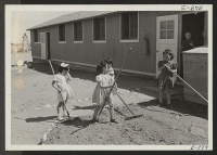 [recto] View showing Elementary children landscaping the grounds in front of their barracks school. ;  Photographer: McClelland, Joe ;  Amache, Colorado.