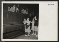 [recto] Girl reporters on the staff of the Topaz Times, publication of the Central Utah Relocation Center, interview new arrivals from Tule Lake through the car windows, while the latter are awaiting to detrain. ;  Photographer: Mace, Charles E. ;  Topaz, Uta